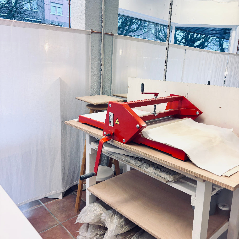 Red slab machine on a table with white material in a room with large windows.