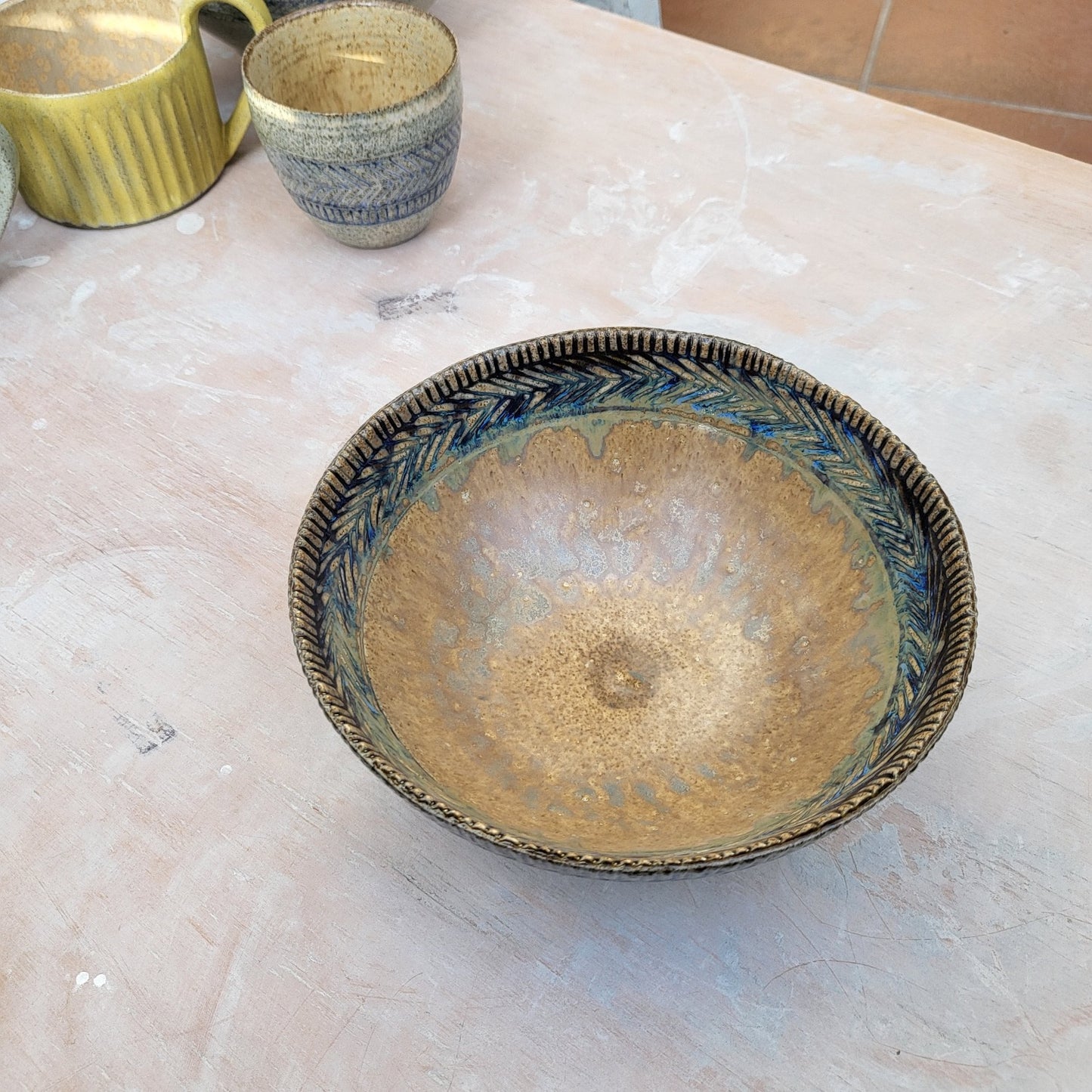 Handmade ceramic bowl with blue carvings.